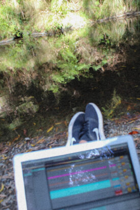 Image of IKSRE's feet and computer screen, sitting by a river at Barham Paradise Reserve